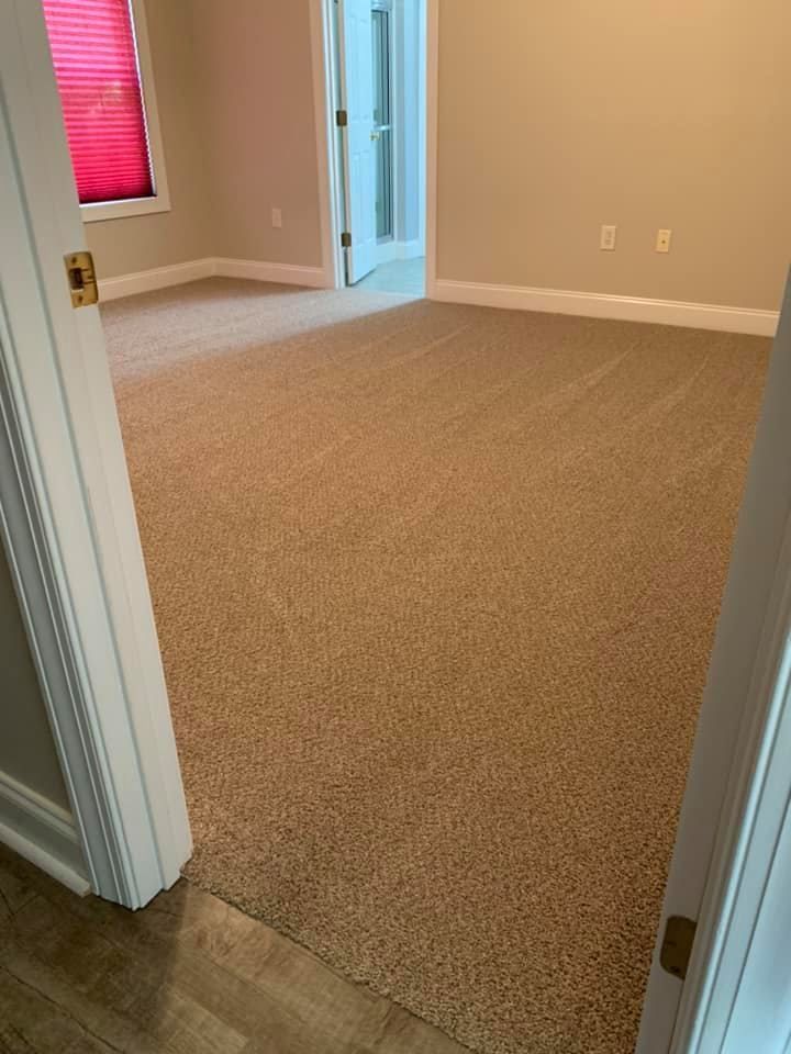A room with a carpeted floor and a doorway leading to a bathroom.