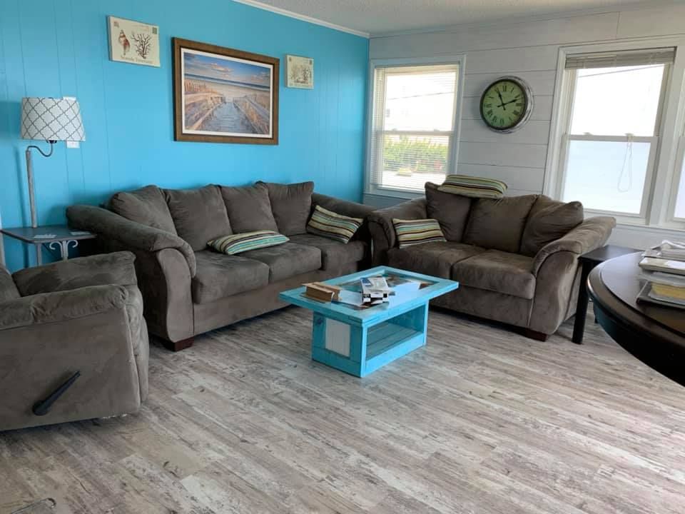 A living room with two couches , a coffee table , and a clock on the wall.