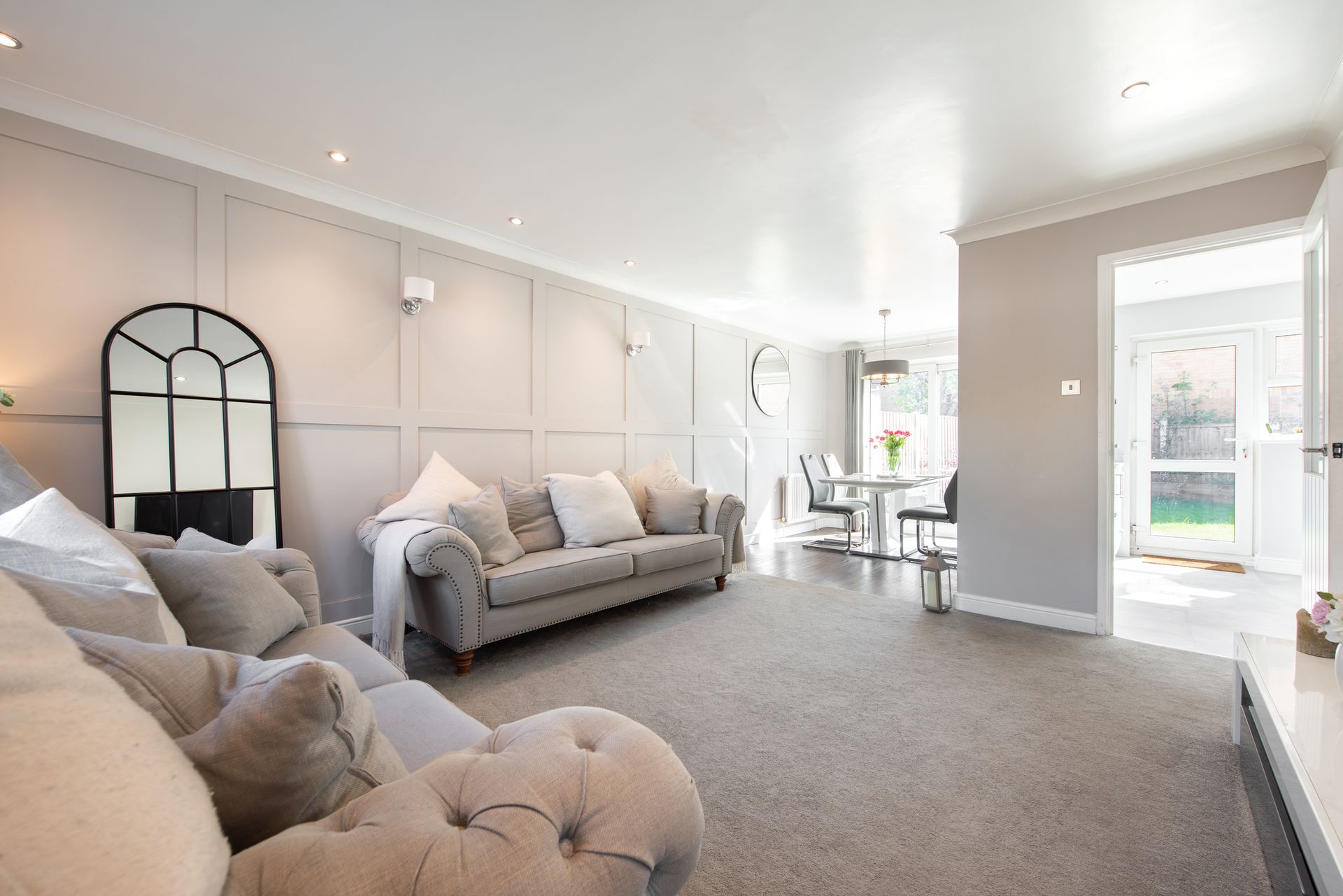A living room with a couch , chair , table and mirror.
