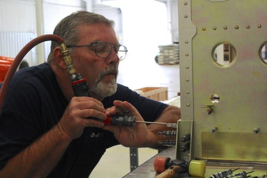A man wearing glasses is working on a piece of metal