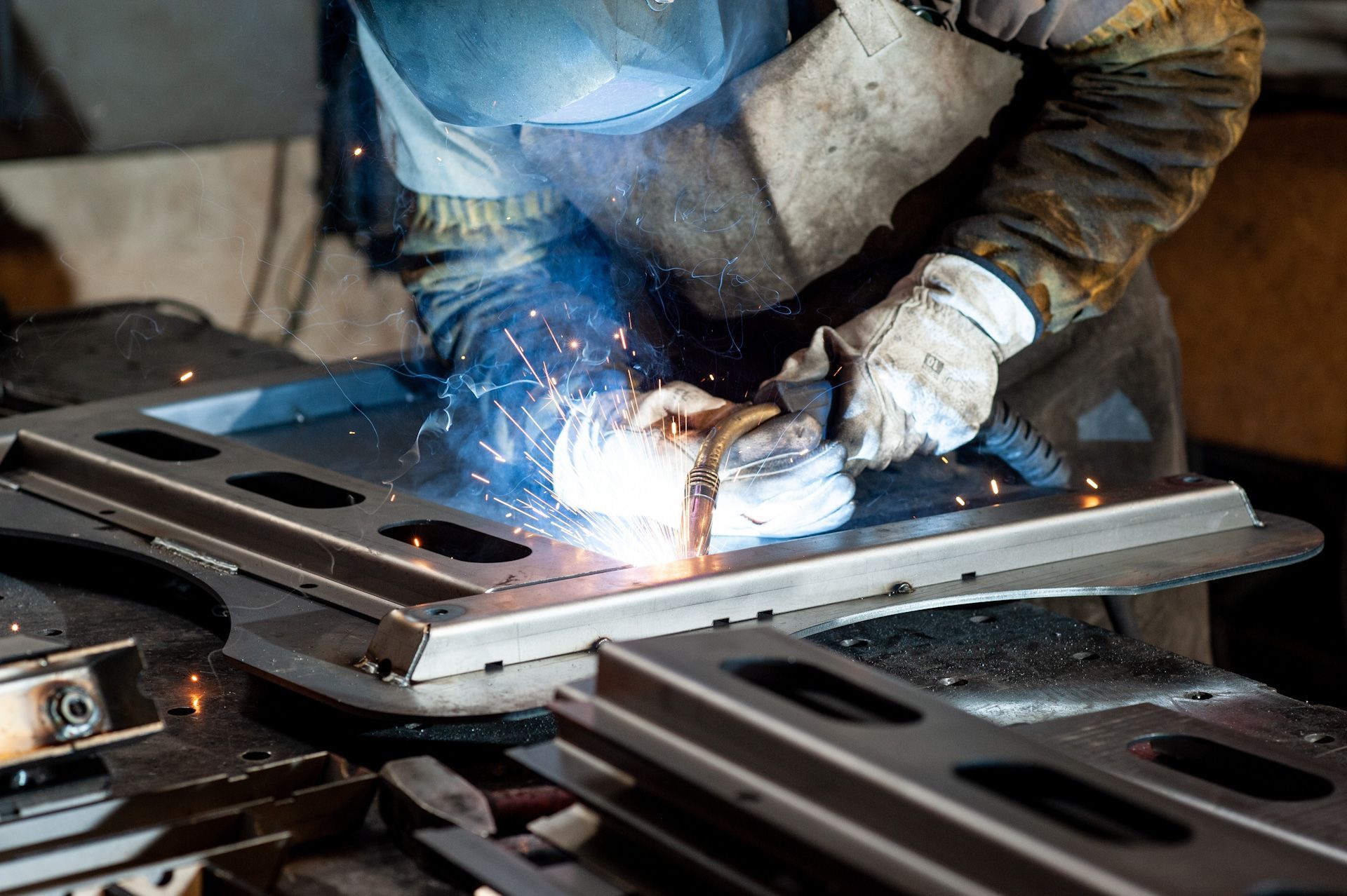A man is welding a piece of metal in a factory.