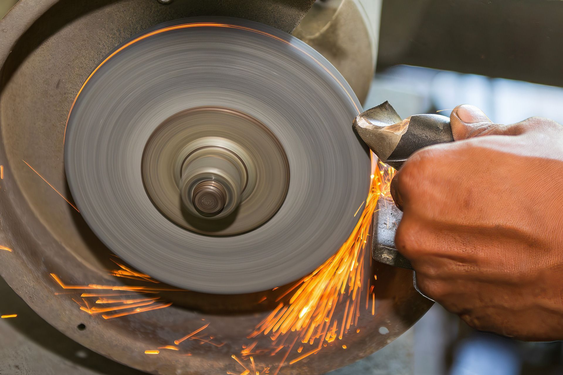 A person is grinding a piece of metal on a machine.