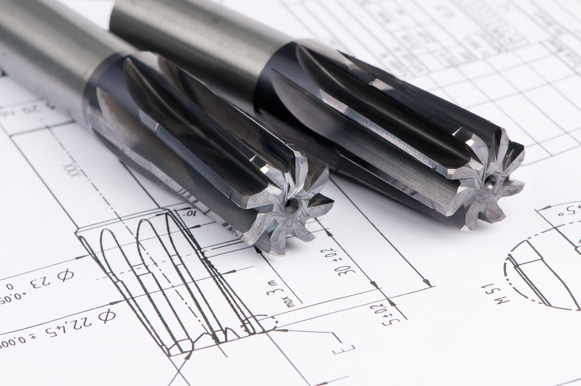 A pair of drill bits laying on top of a drawing
