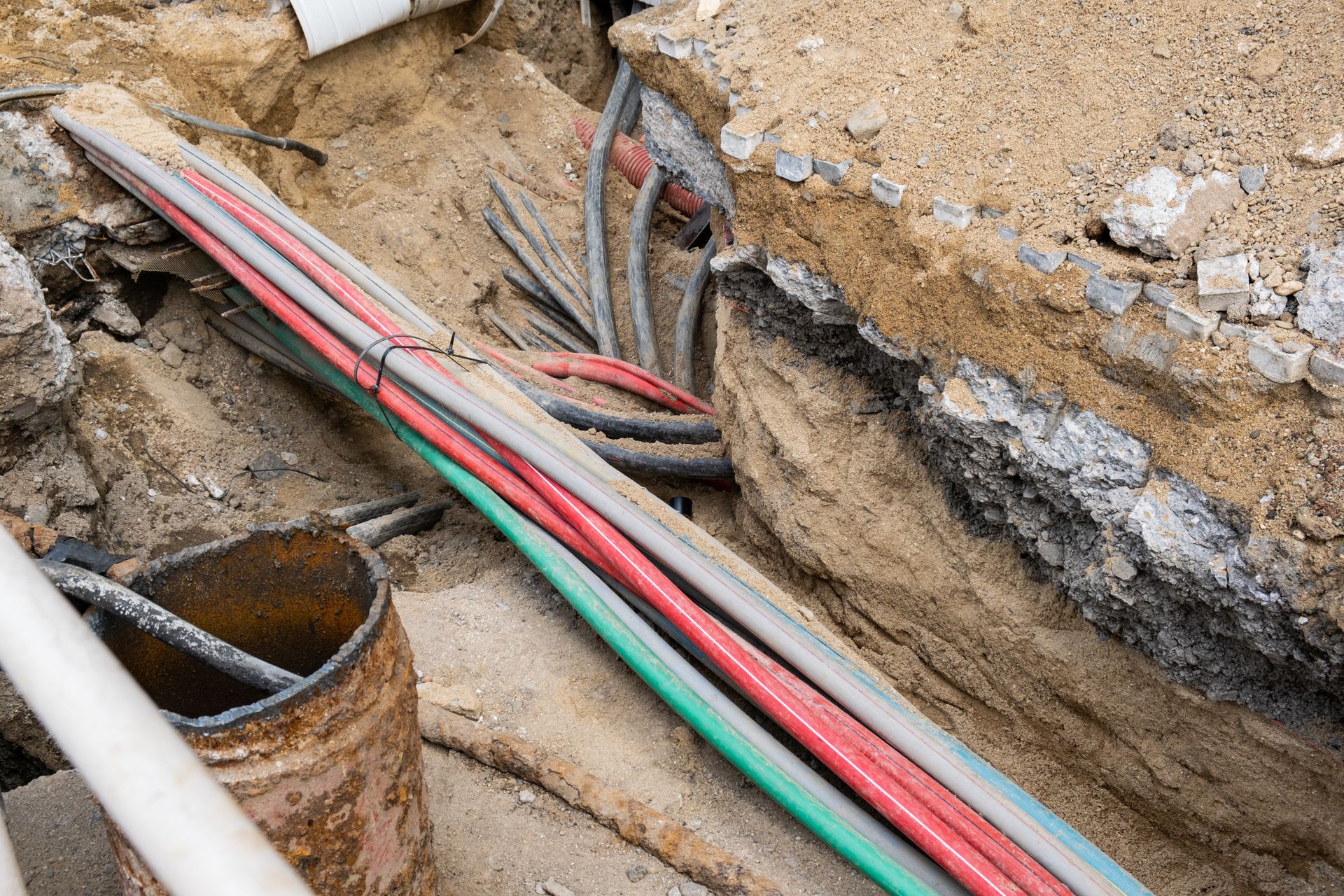 A bunch of electrical wires are laying in the dirt.