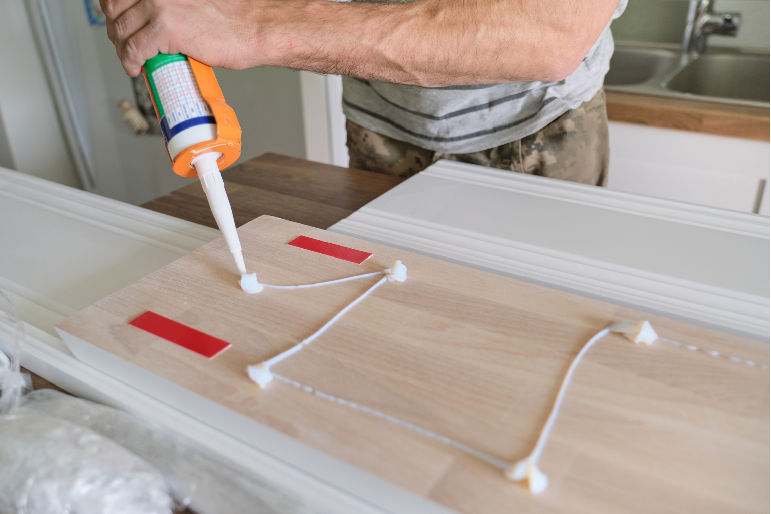 A man is applying glue to a piece of wood.
