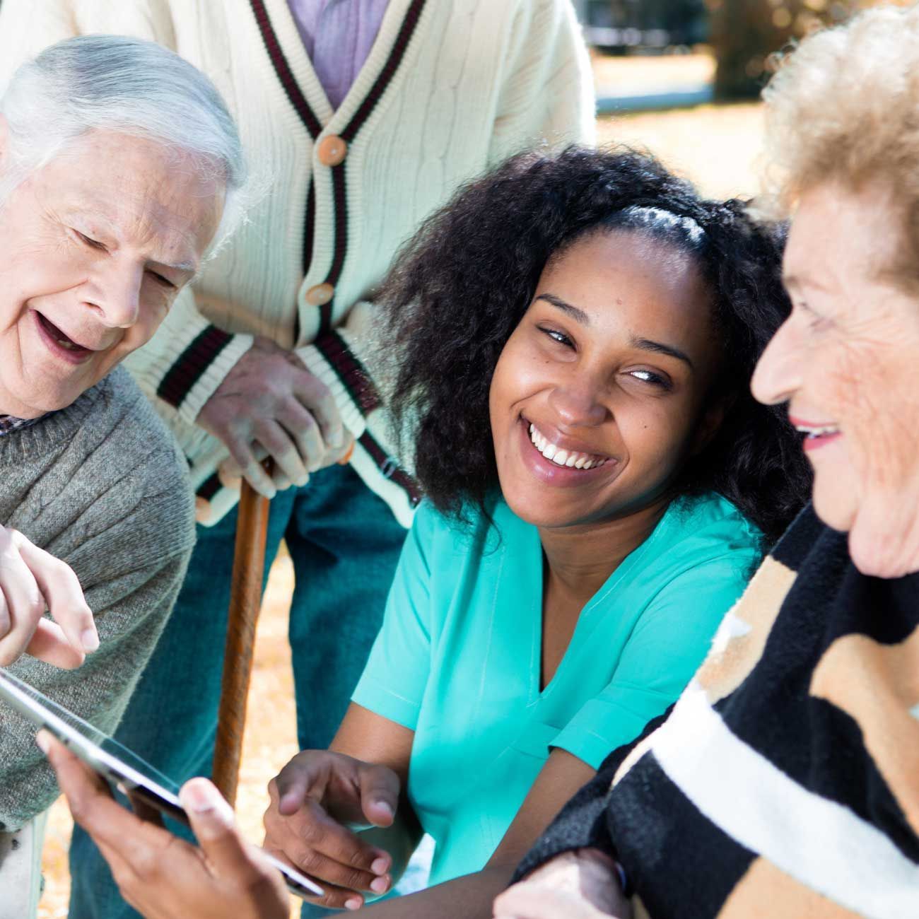 Group of people smiling and looking at a tablet during a friendly discussion