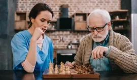 Two people concentrating over a chess game at a wooden table in a cozy café.