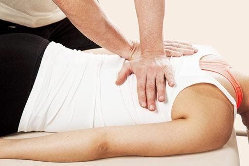 A woman is laying on a table getting a massage from a man.