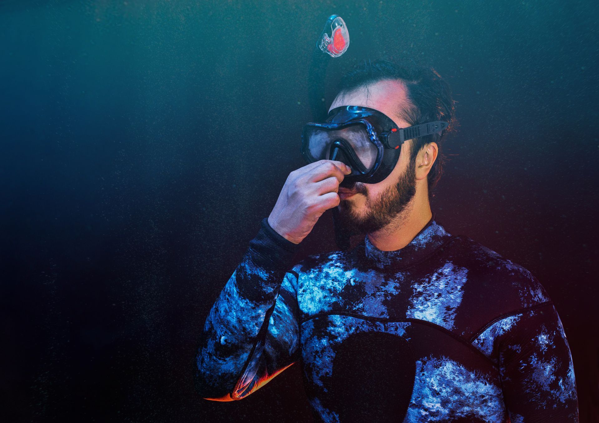 A man with a beard is wearing a diving suit and goggles.