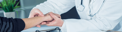 A doctor is holding the hand of a patient.