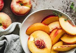 A bowl of sliced peaches with a fork in it.