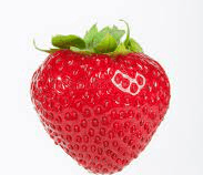 A close up of a strawberry with a sticker on it on a white background.