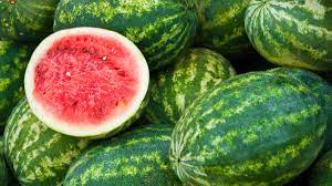 A pile of watermelons with one cut in half.