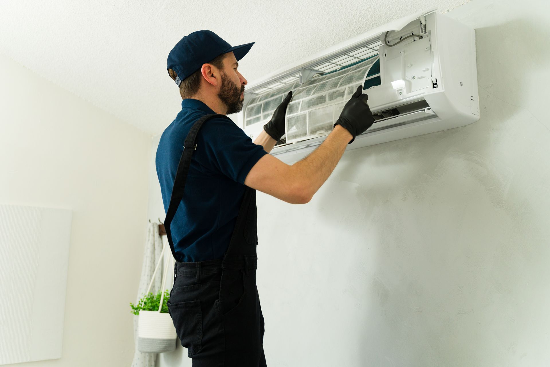 Contractor lifting the front panel to service a wall AC unit.