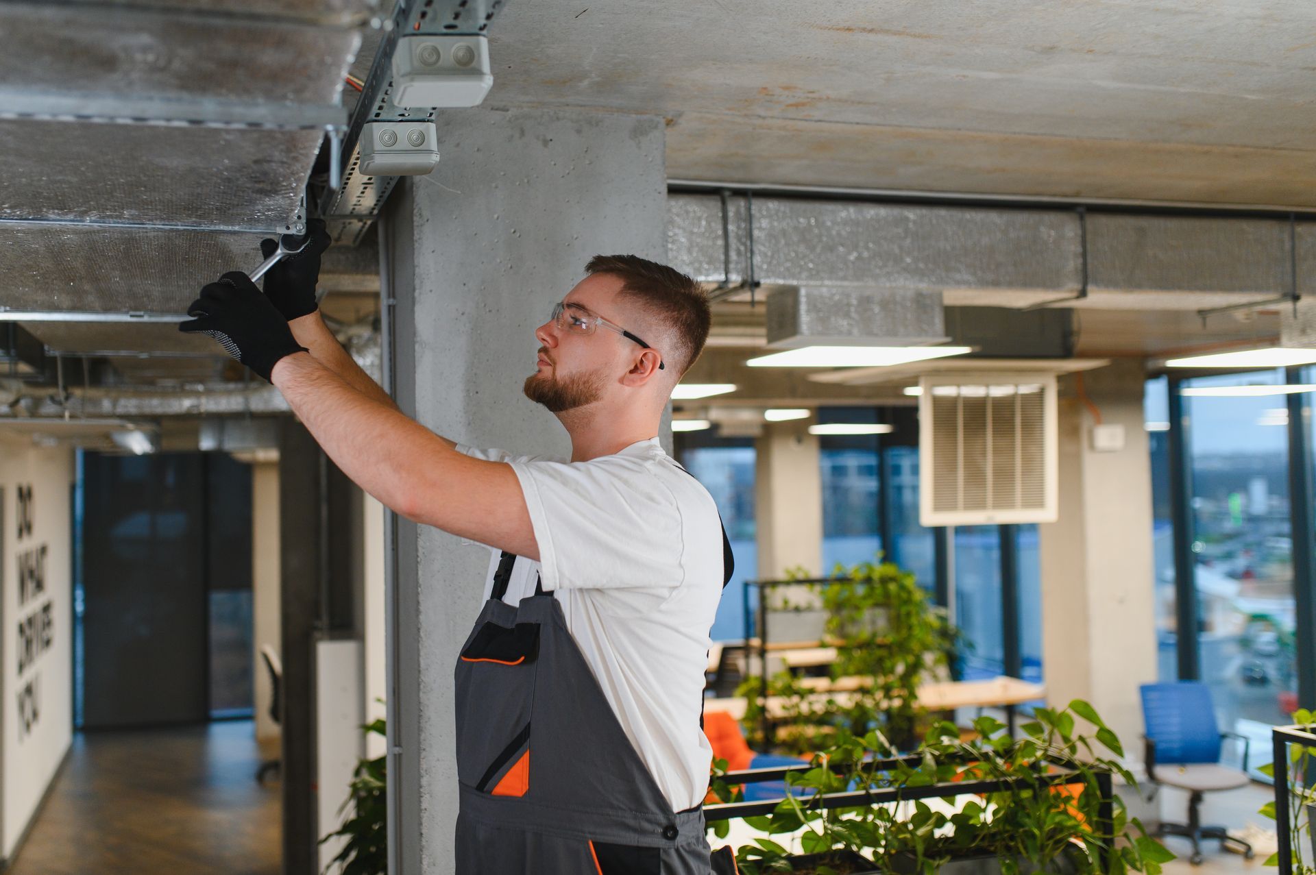 HVAC technician installing ventilation ductwork in office.