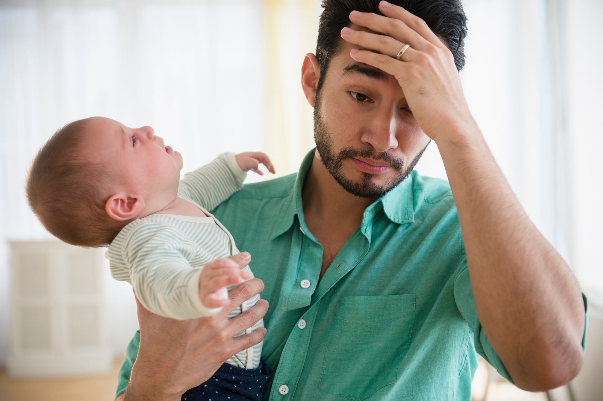 A Man is Holding a Crying Baby in his Arms — Alexander Law Firm in ST Pickens