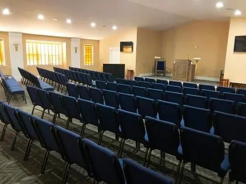 Blue chairs arranged in rows in a church interior, altar at the front with pulpit.