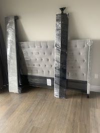 A bedroom with a mattress and headboard wrapped in plastic.