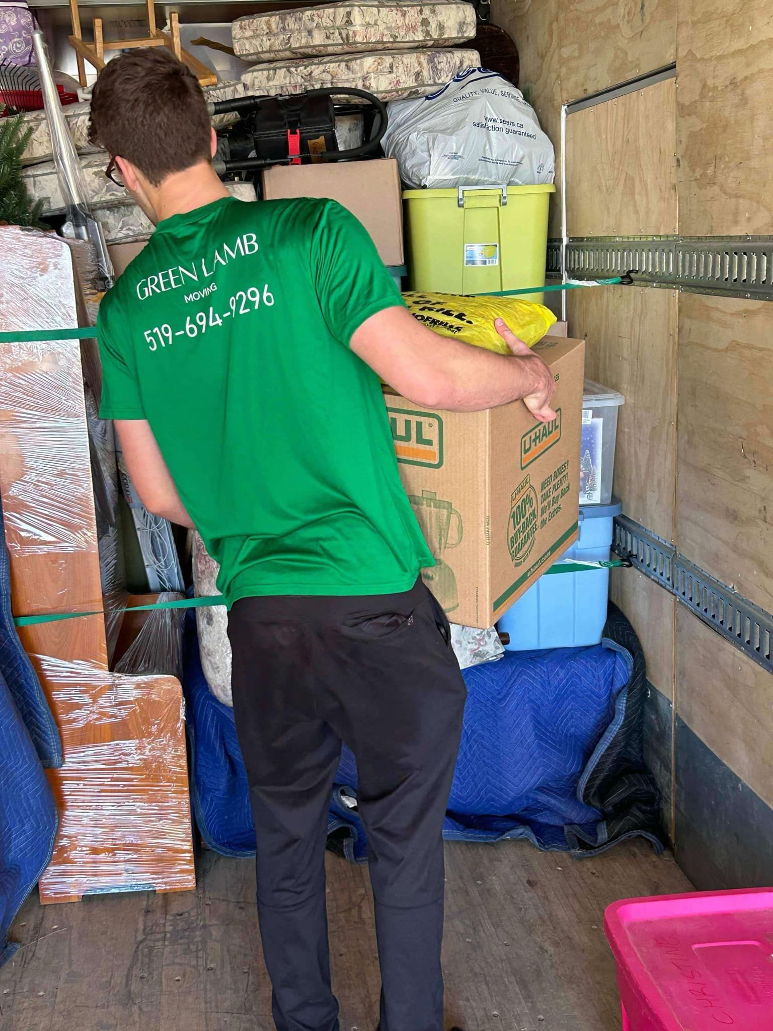 A man in a green shirt is loading boxes into a truck.
