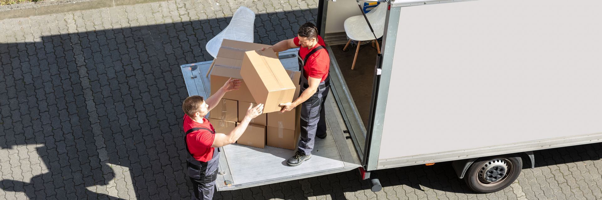 Two men are loading boxes into a moving truck.