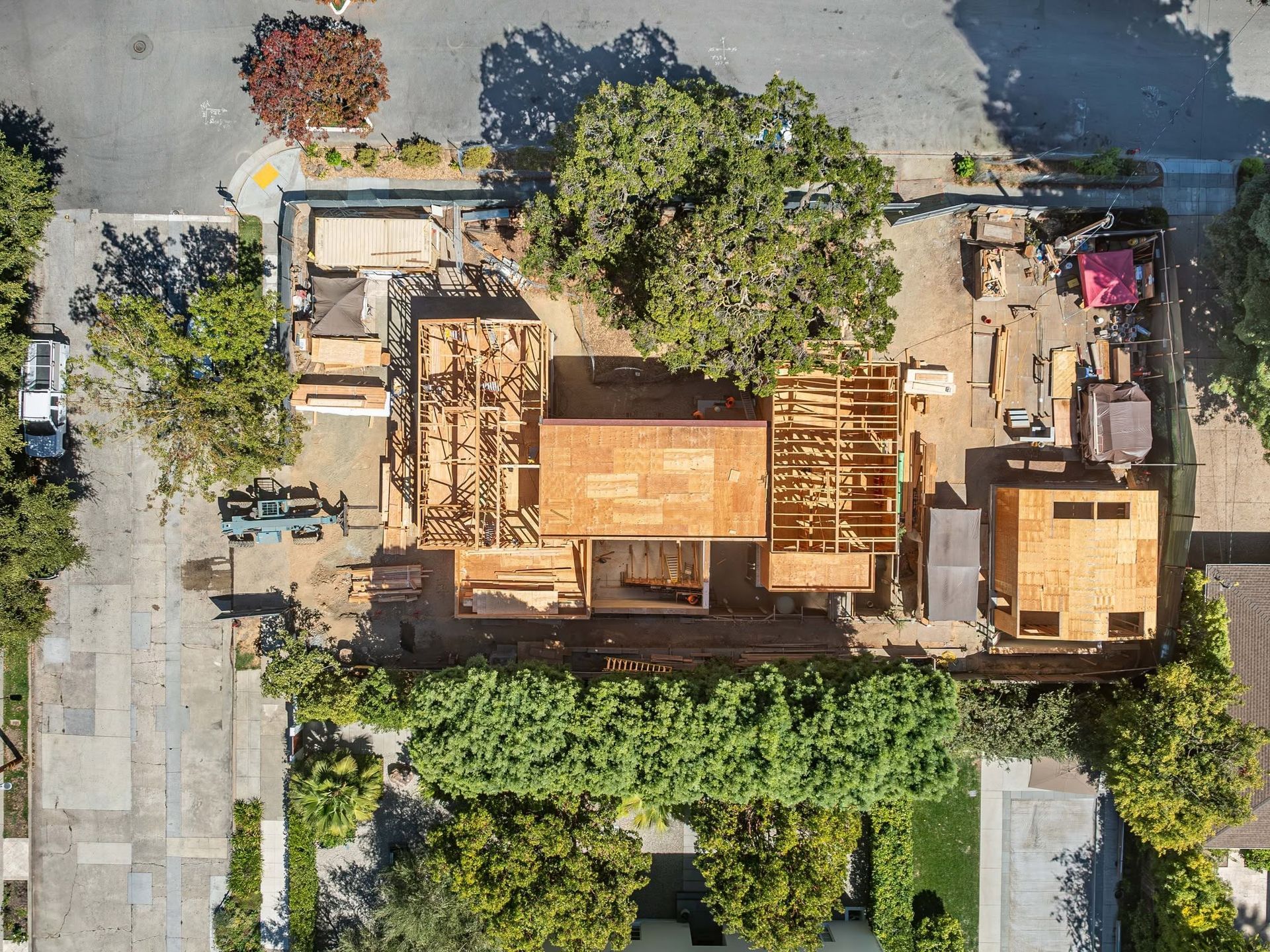 Aerial view of a small wooden building and garden beside a paved walkway and trees.