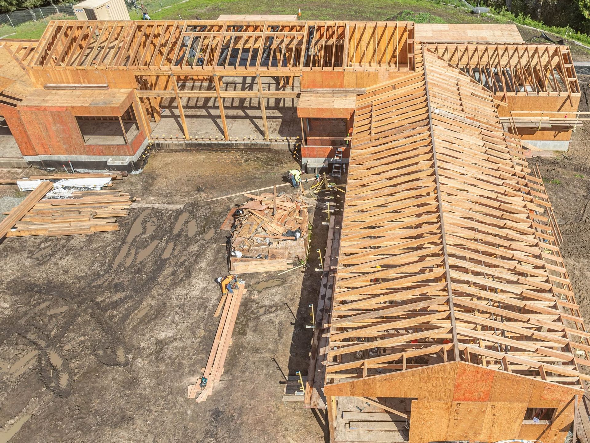 Aerial view of a building under construction with exposed wooden framing and roofing trusses.