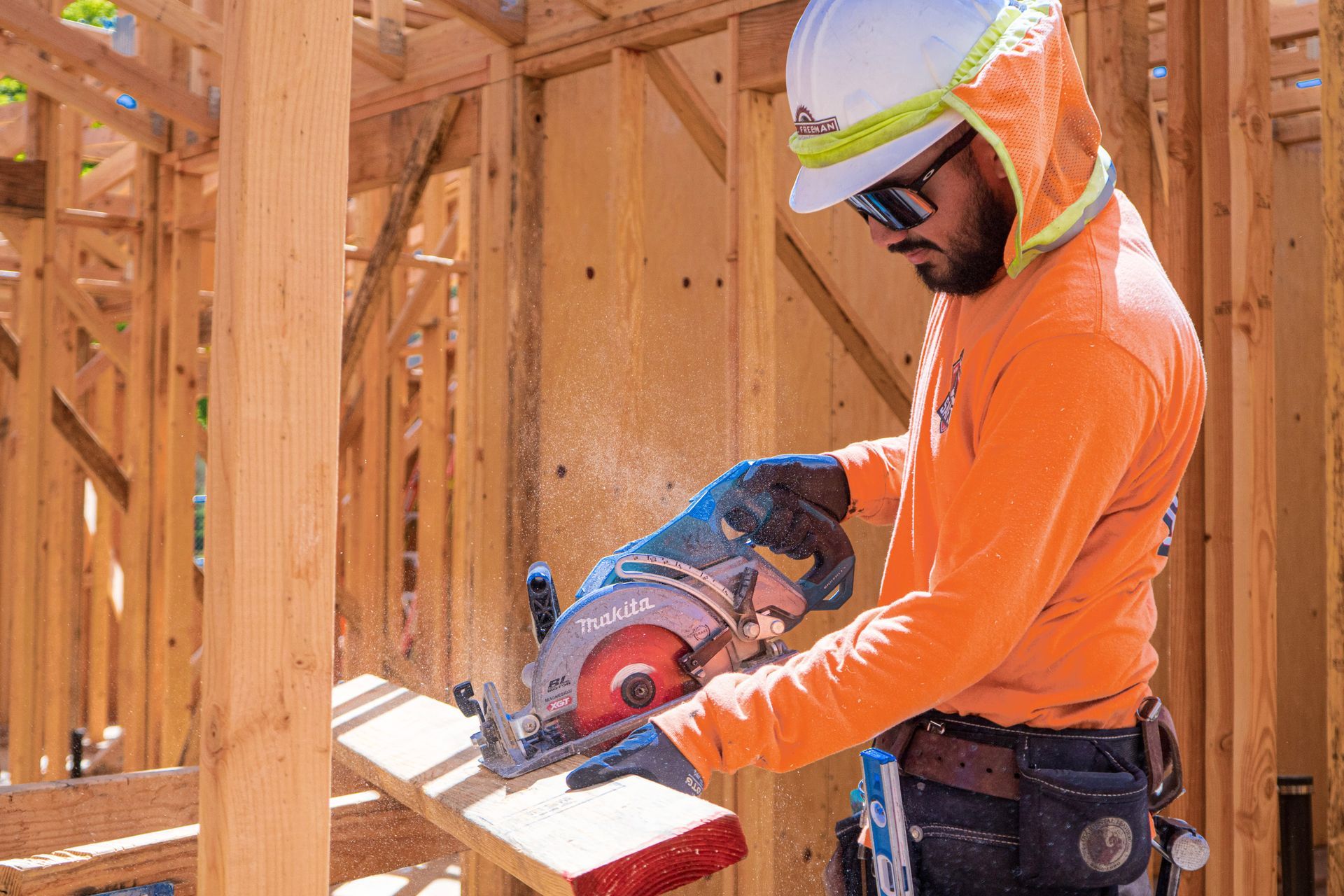 Worker using a circular saw on lumber inside a framed wooden structure