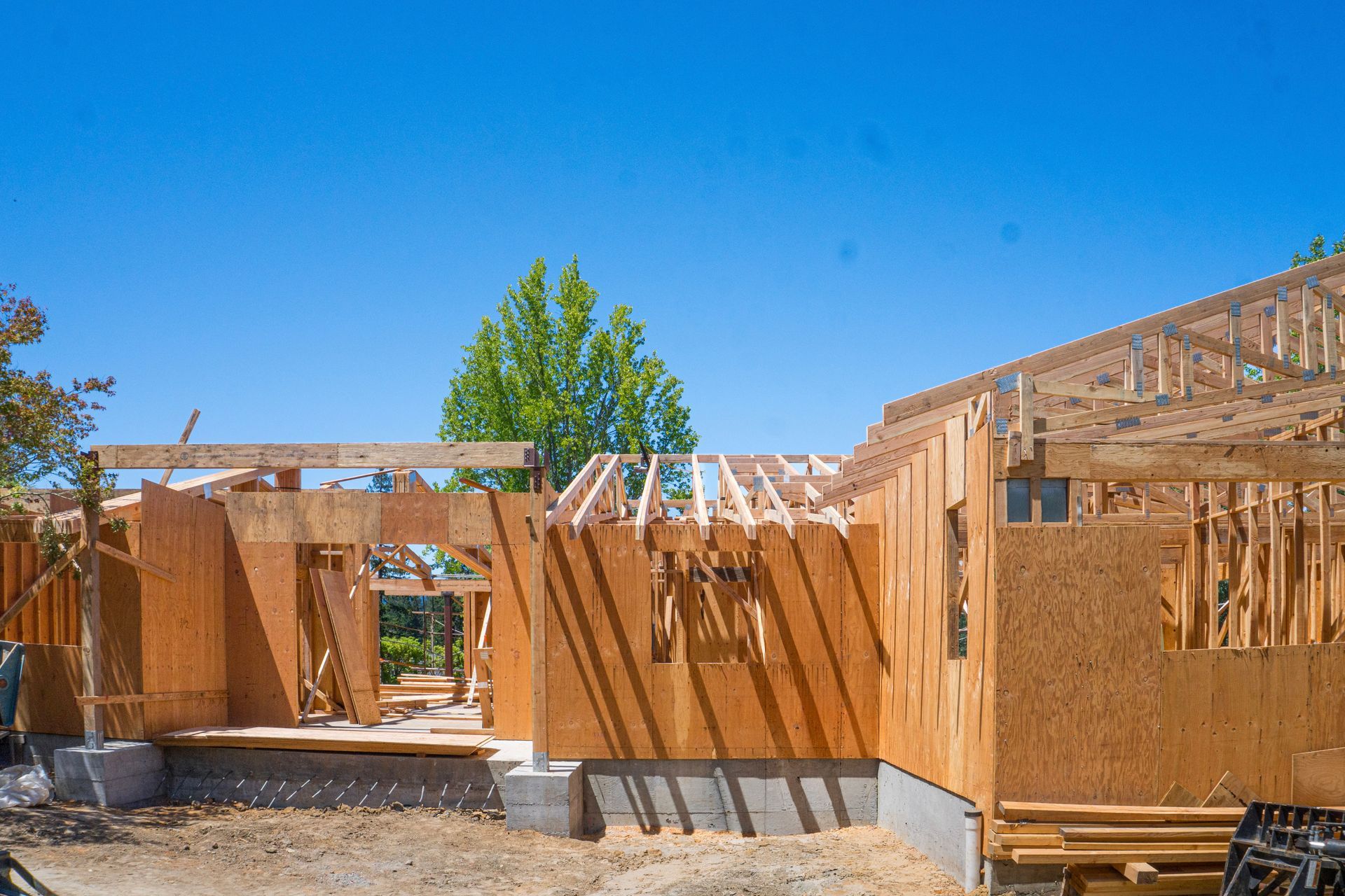 Partially framed house under construction against a clear blue sky