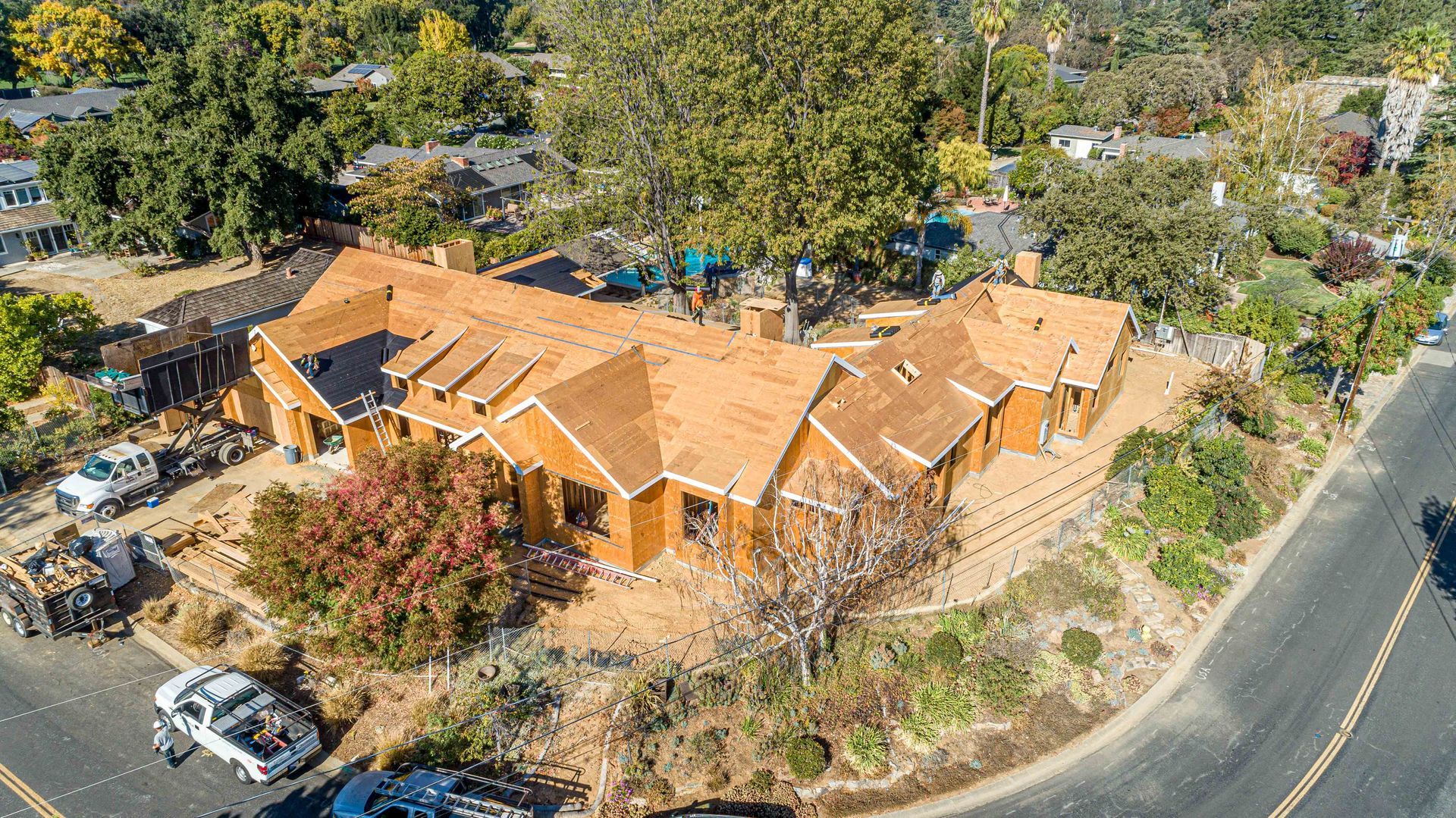 Aerial view of a large orange-roofed house surrounded by trees beside a curved road.