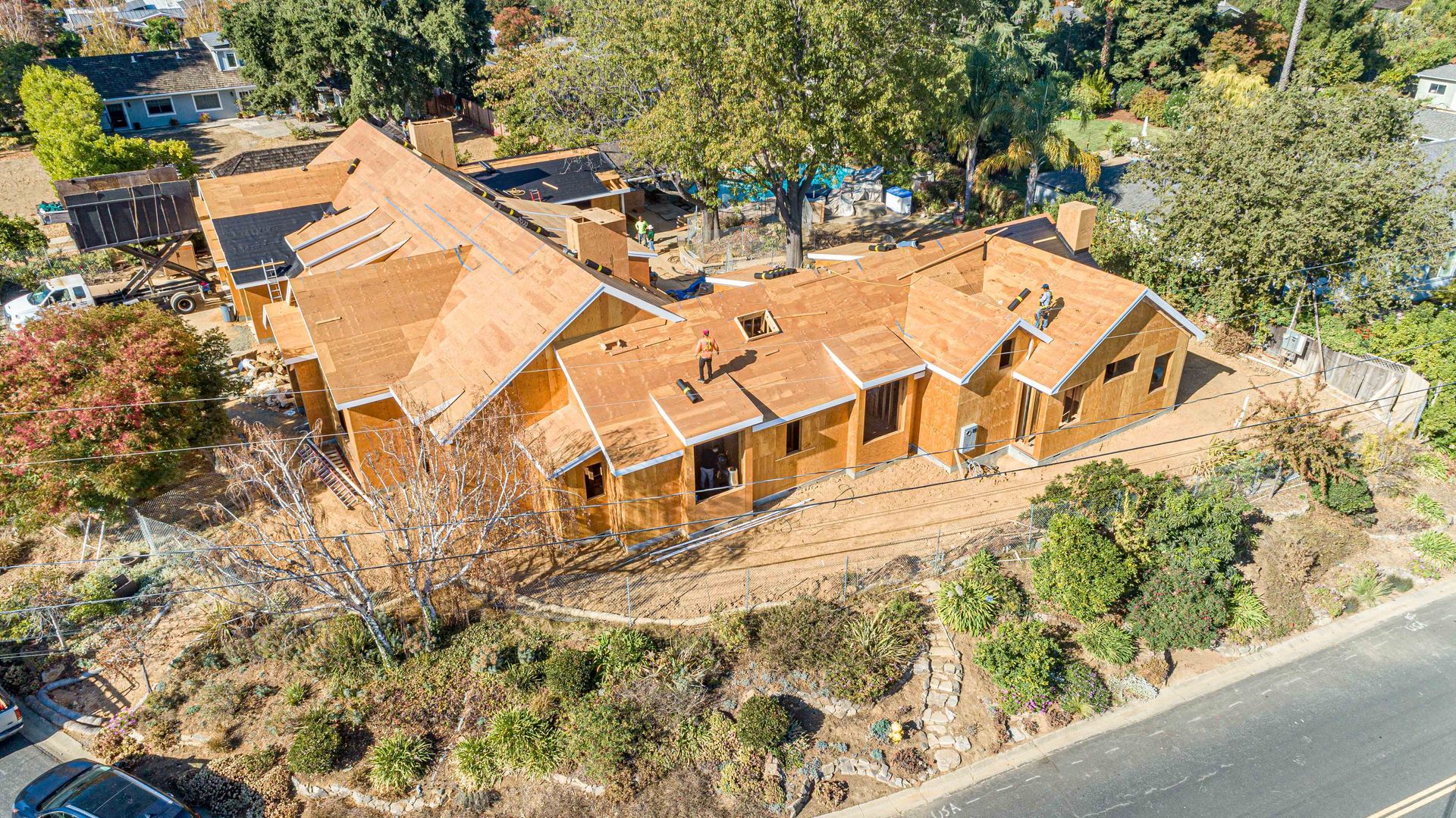 Aerial view of a tan-roofed house with trees and a road nearby.
