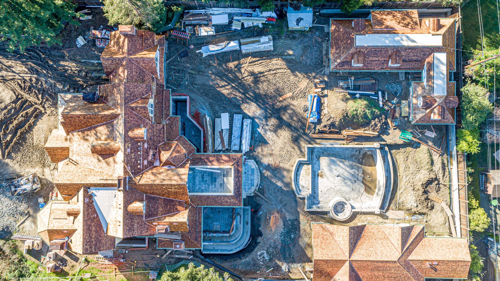 Aerial view of a dense neighborhood with rooftops, trees, and dirt roads