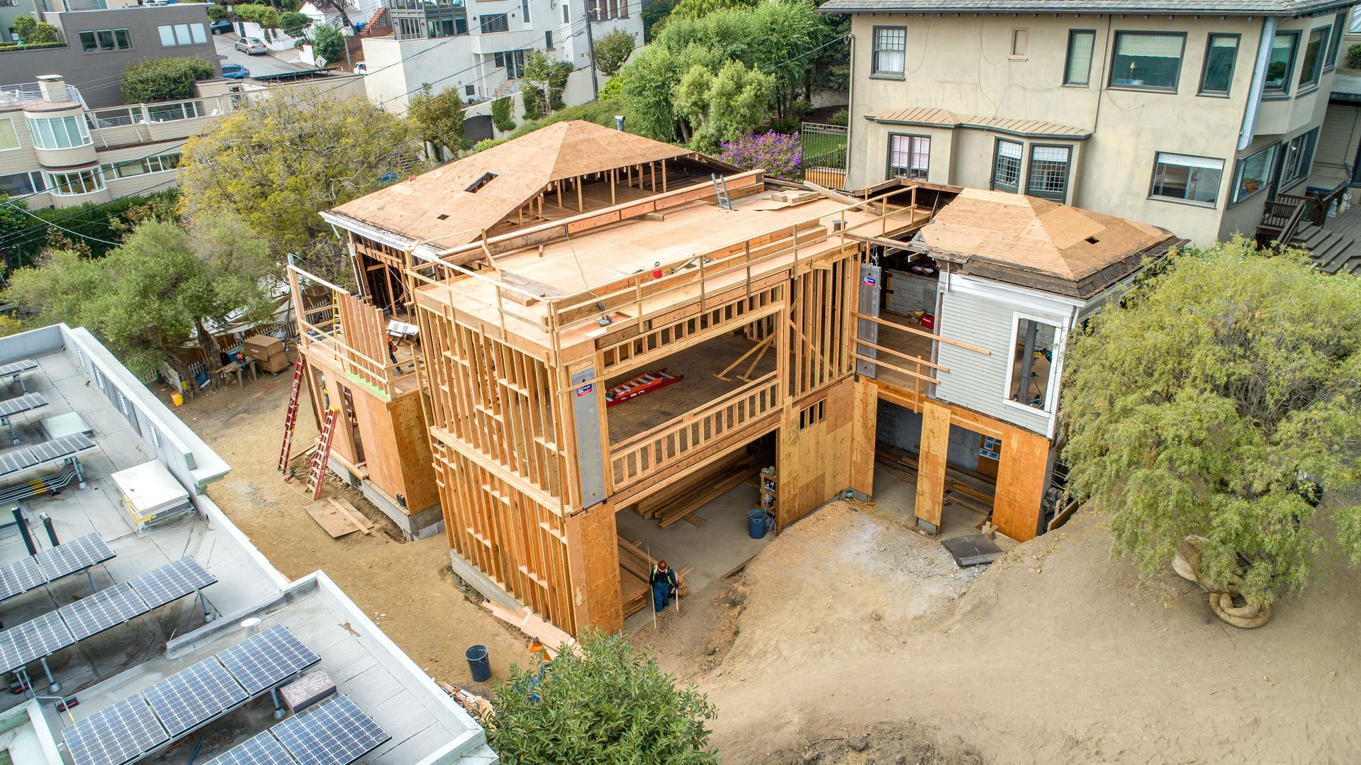Wood-framed house under construction in a residential neighborhood, viewed from above