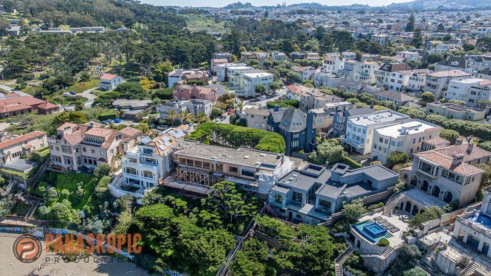 Aerial view of a suburban neighborhood with homes, trees, and a winding road under a clear sky