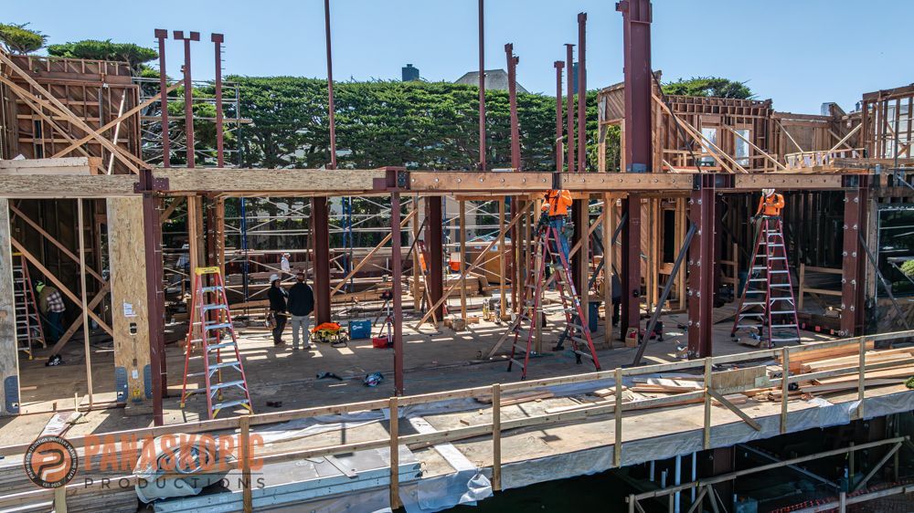 Construction site with wooden framing, scaffolding, and workers under bright daylight