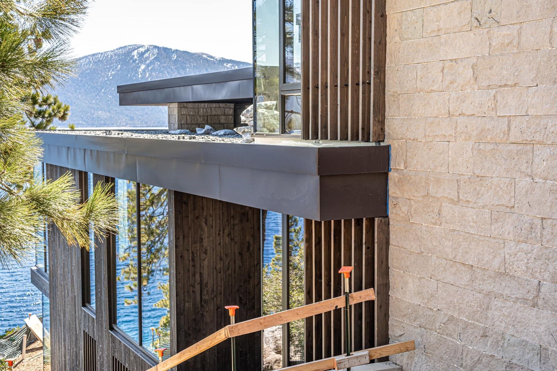 Modern building balcony with glass railings and a mountain view beyond the stone facade