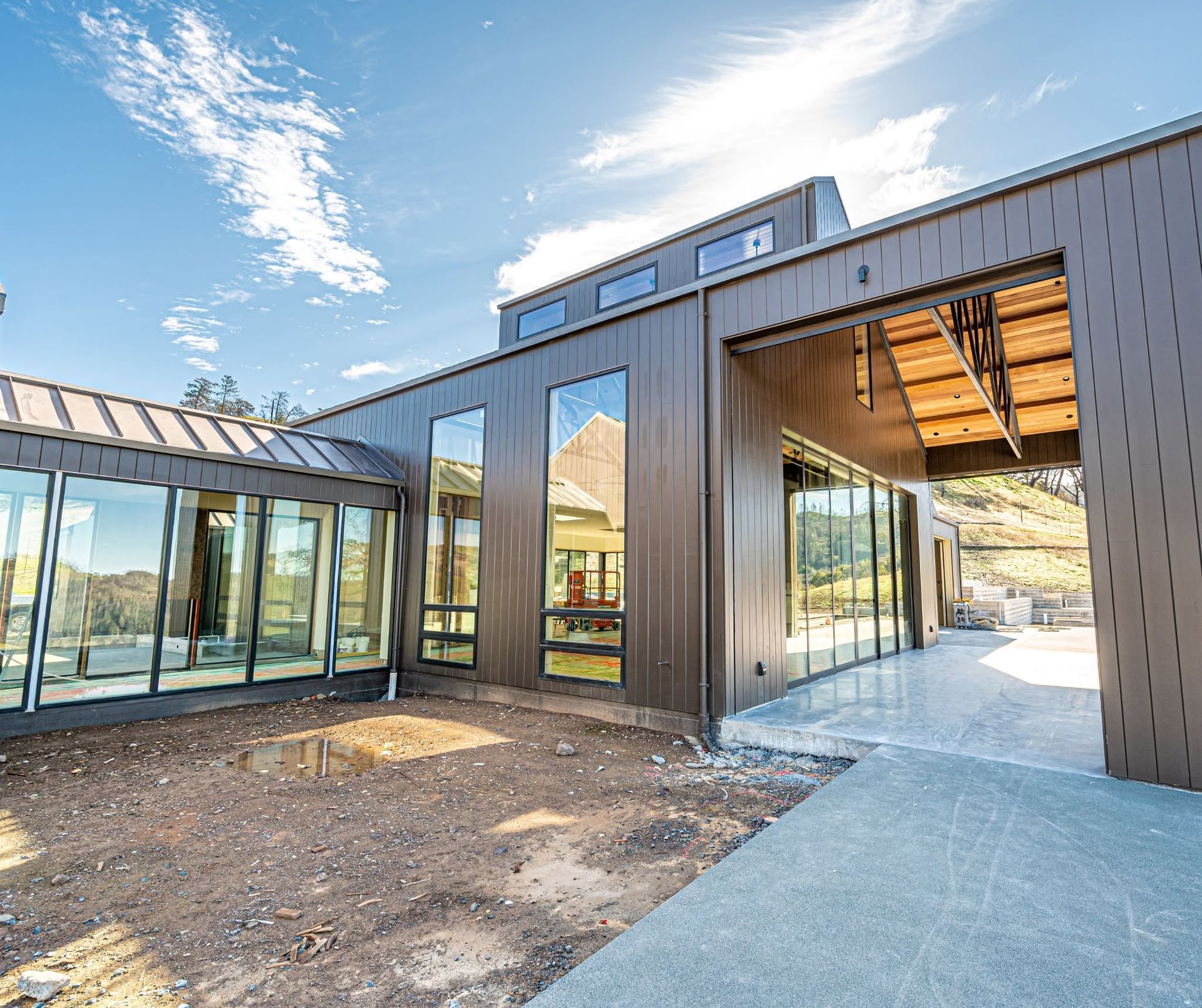 Modern house exterior with large glass walls, wood siding, and a covered walkway at the entrance