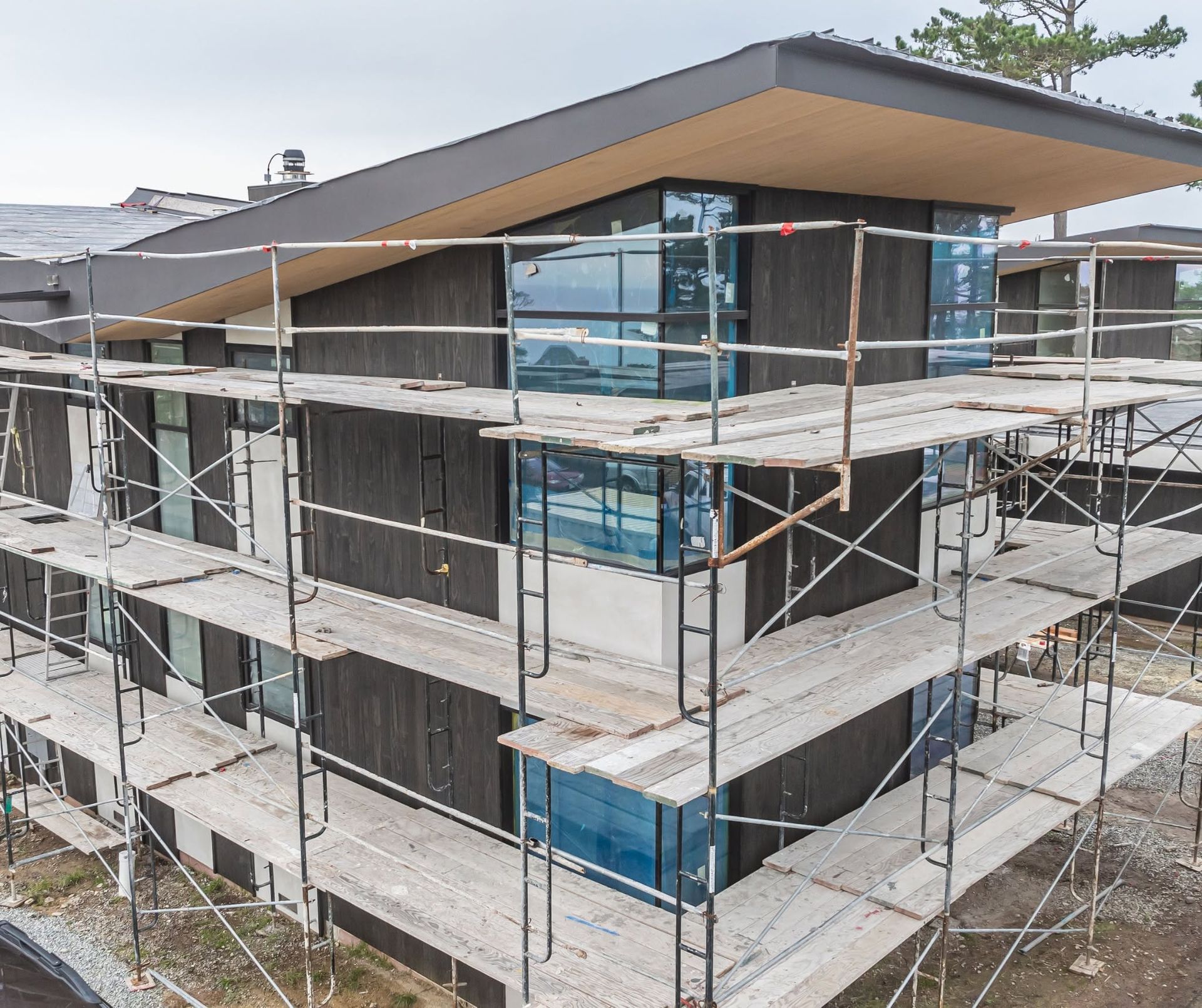 Modern multi-story building under construction with scaffolding and exposed glass фасade