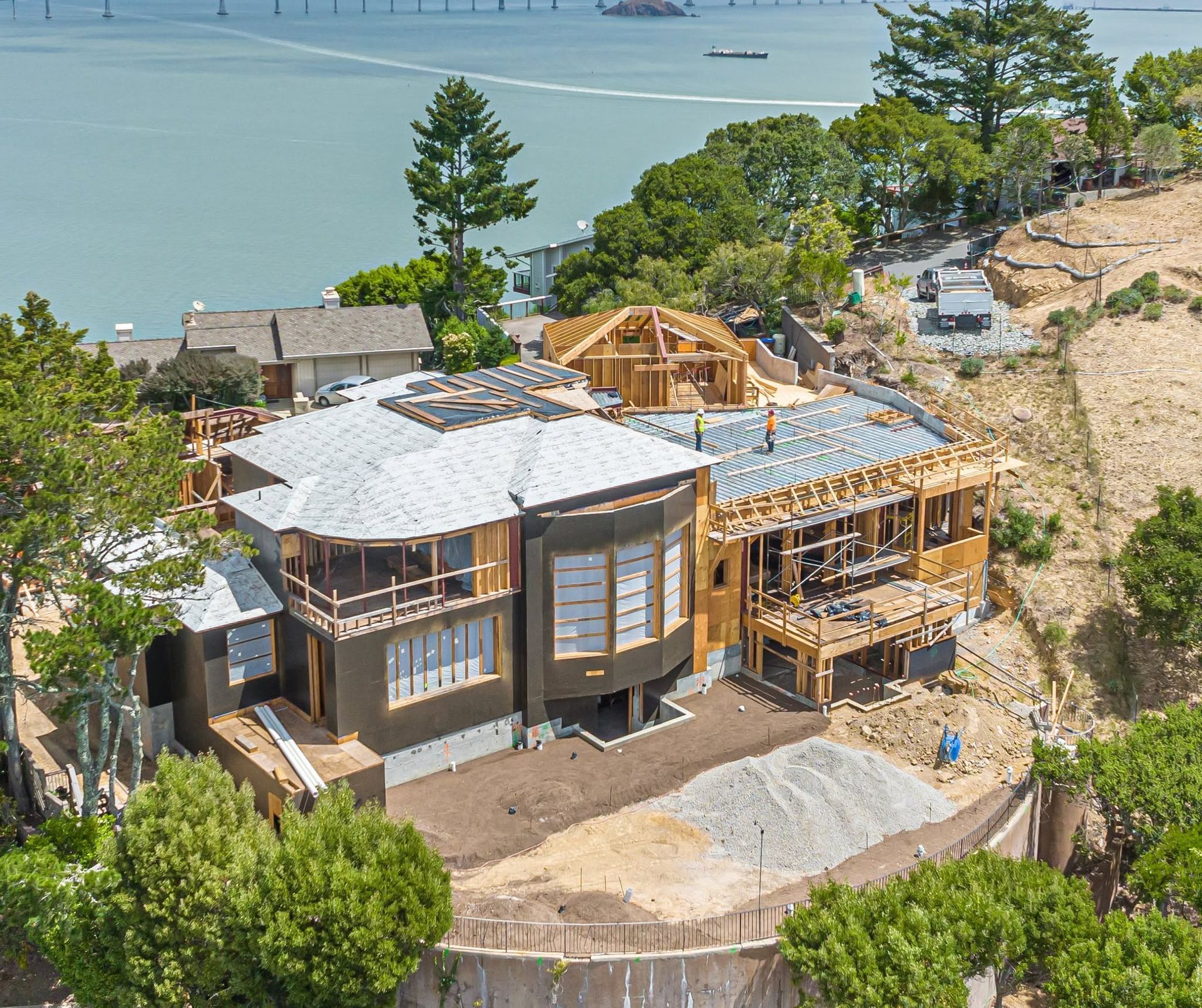 House under construction on a wooded hillside overlooking the water