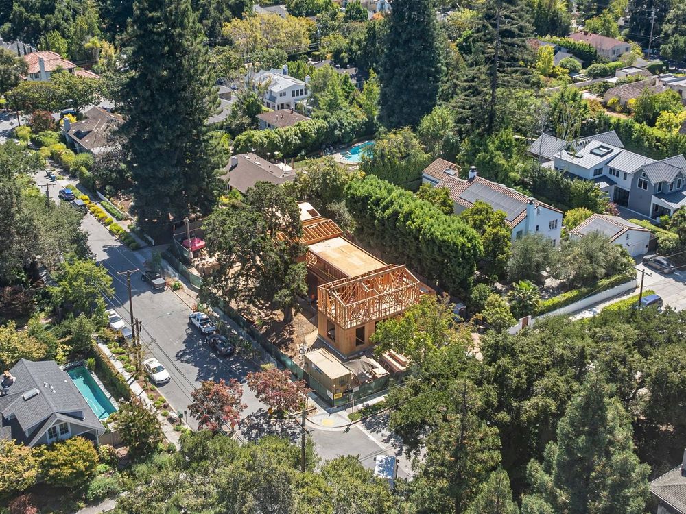 Aerial view of a tree-lined suburban neighborhood with houses and a street under construction.