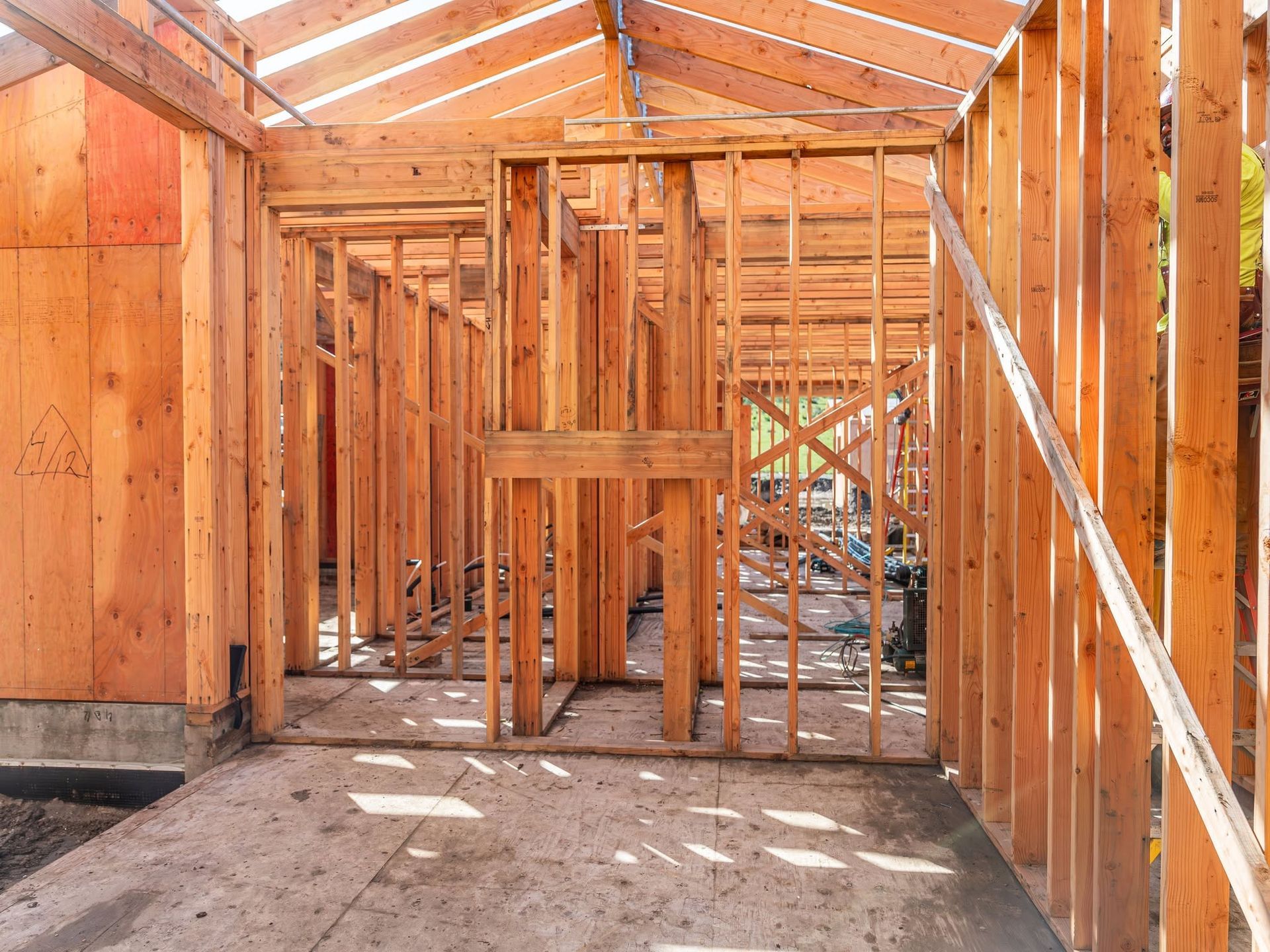 Interior of a wooden house under construction with exposed framing and unfinished floorboards