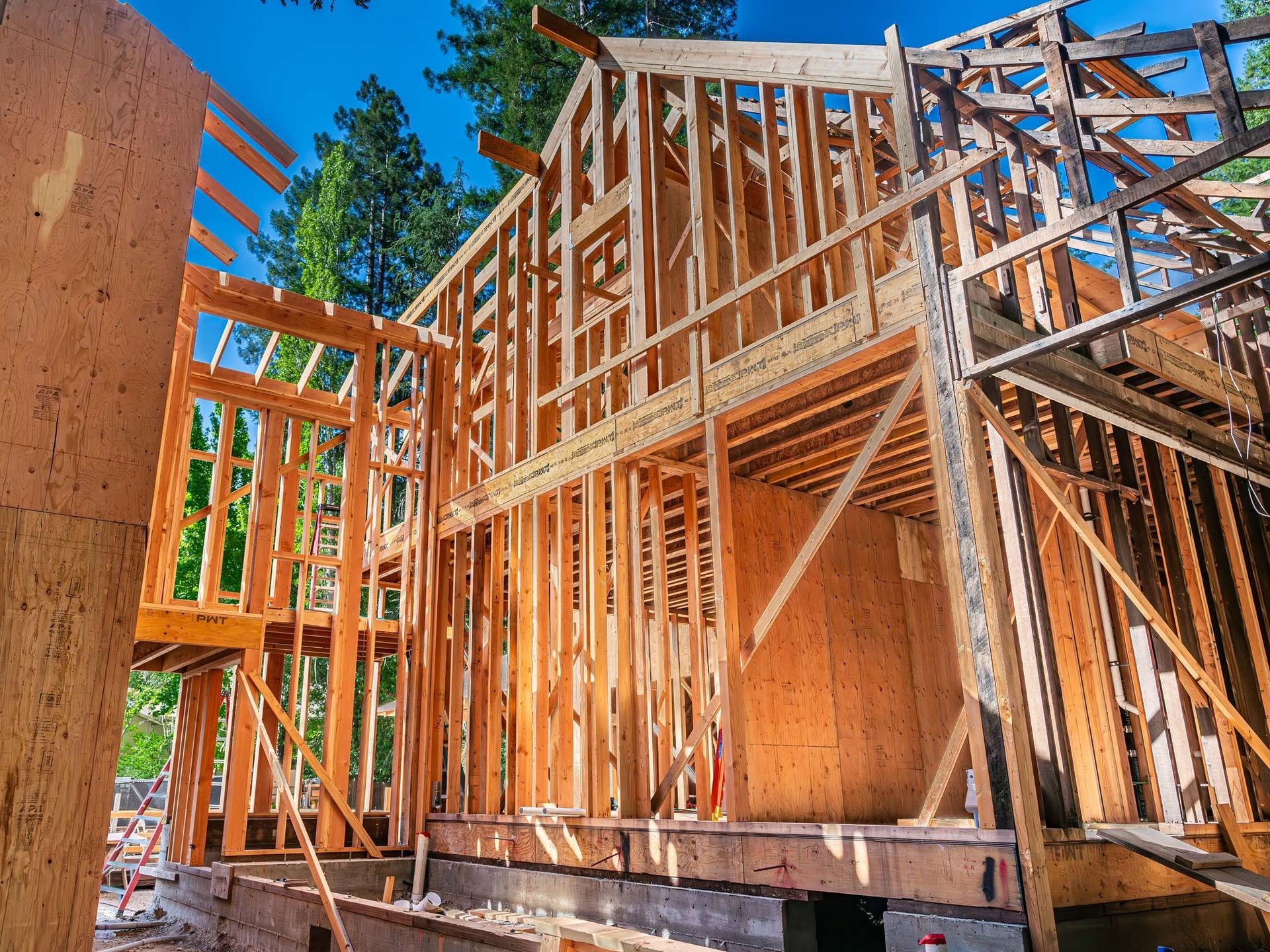 Wood-framed house under construction with plywood sheathing and blue sky in the background