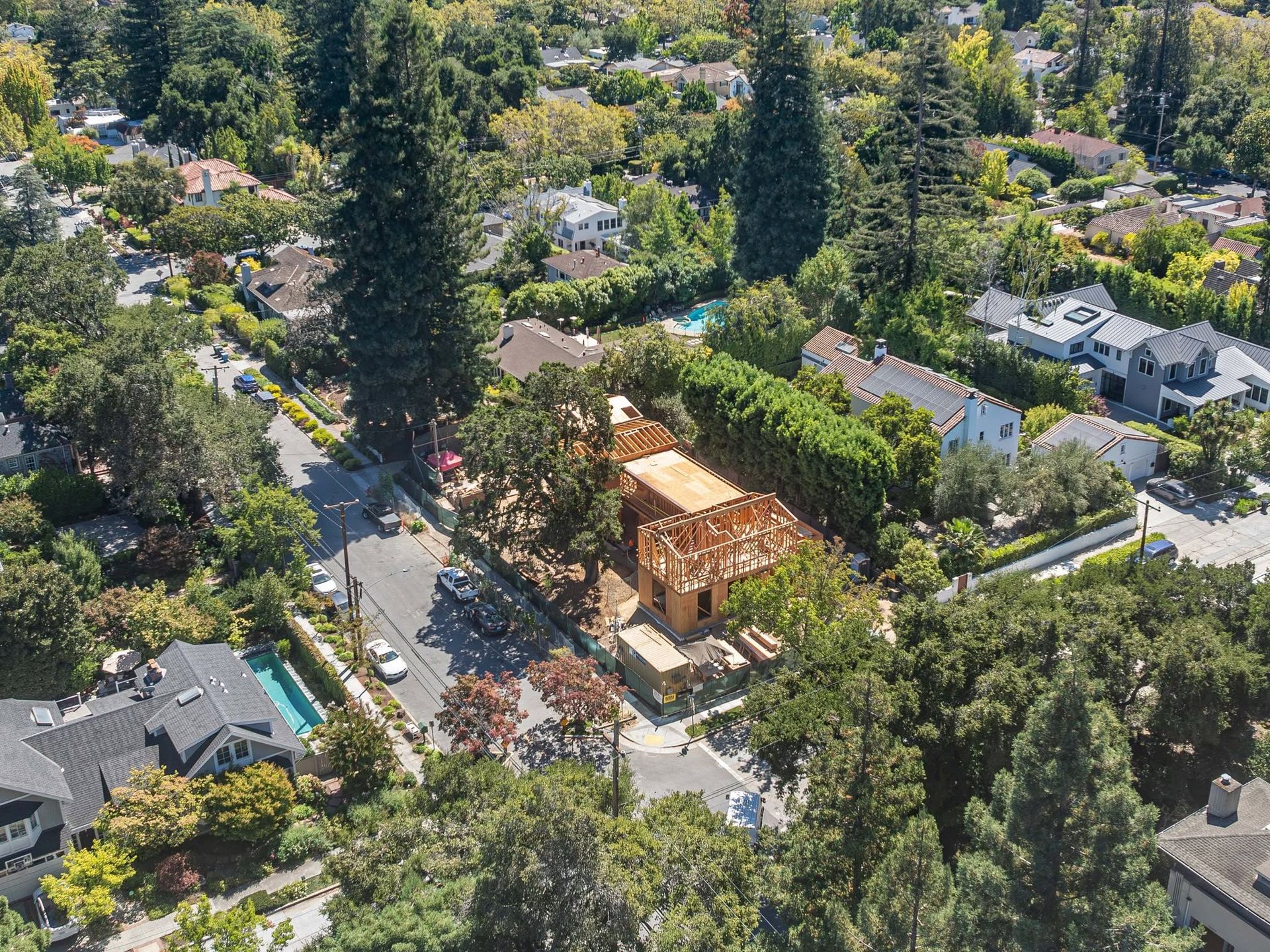 Aerial view of a suburban neighborhood with tree-lined streets, houses, and a building under construction.