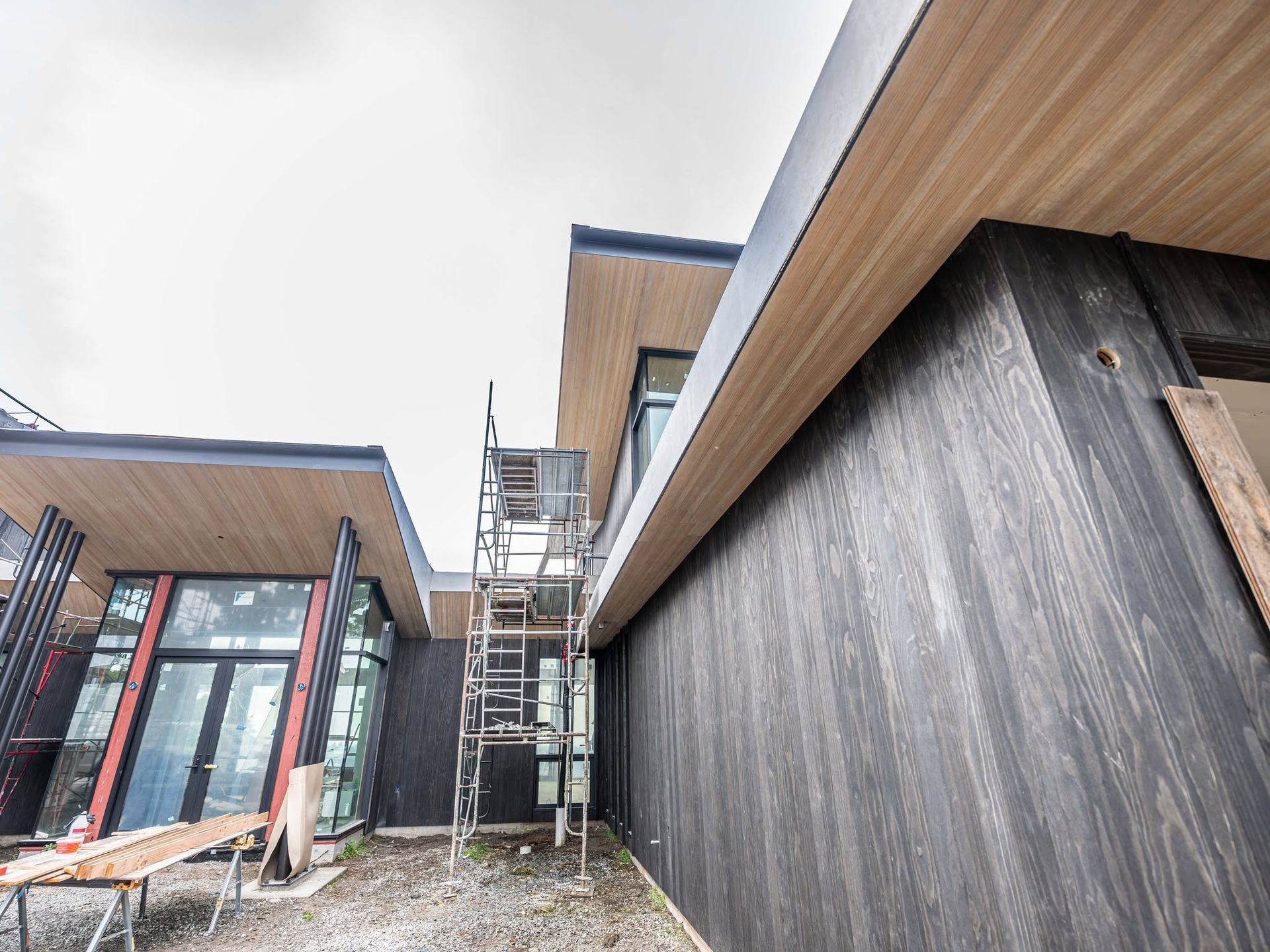 Modern houses under construction with scaffolding between dark wood and glass facades