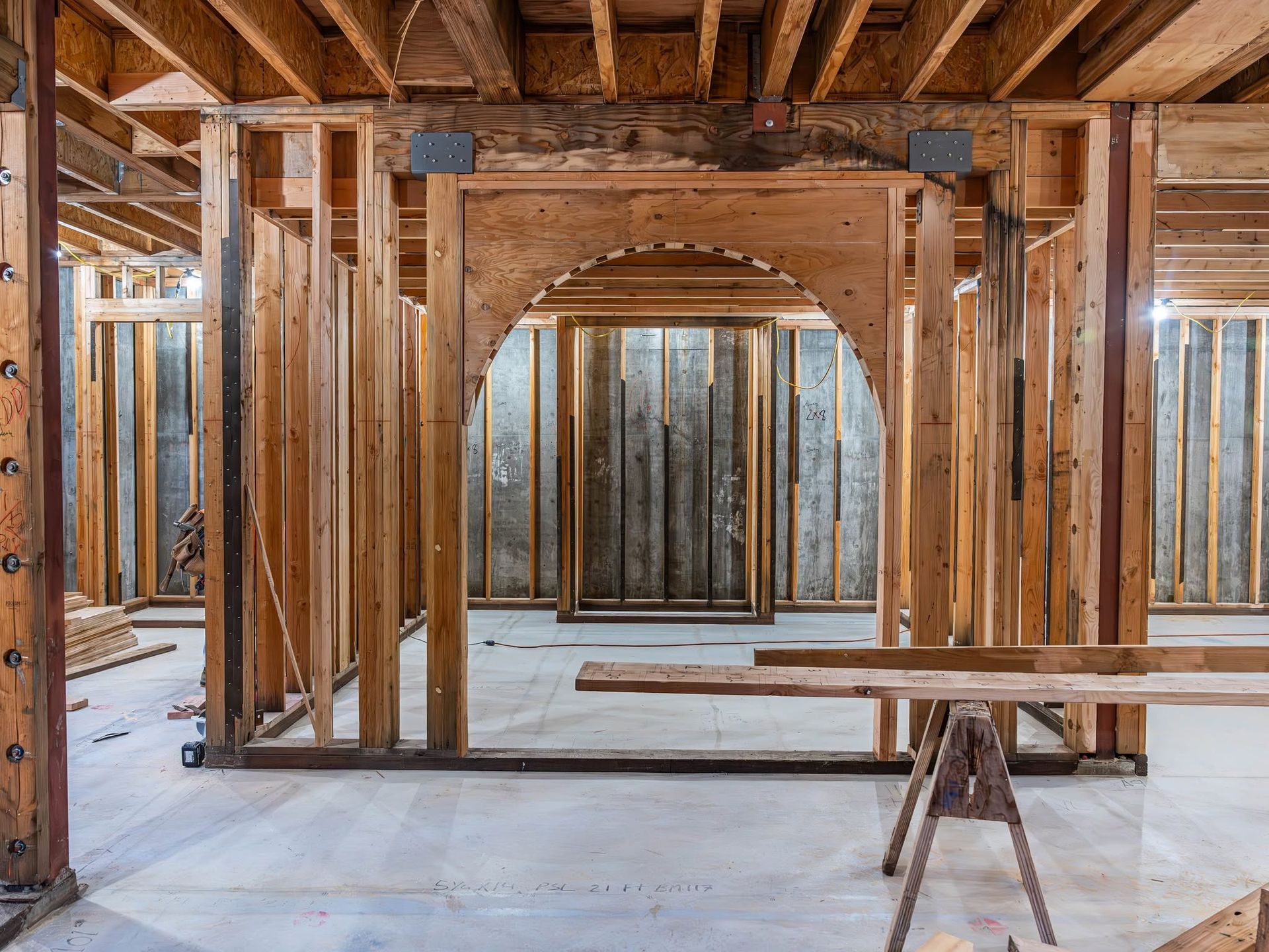 Interior of a wooden building under construction with exposed framing and concrete floor