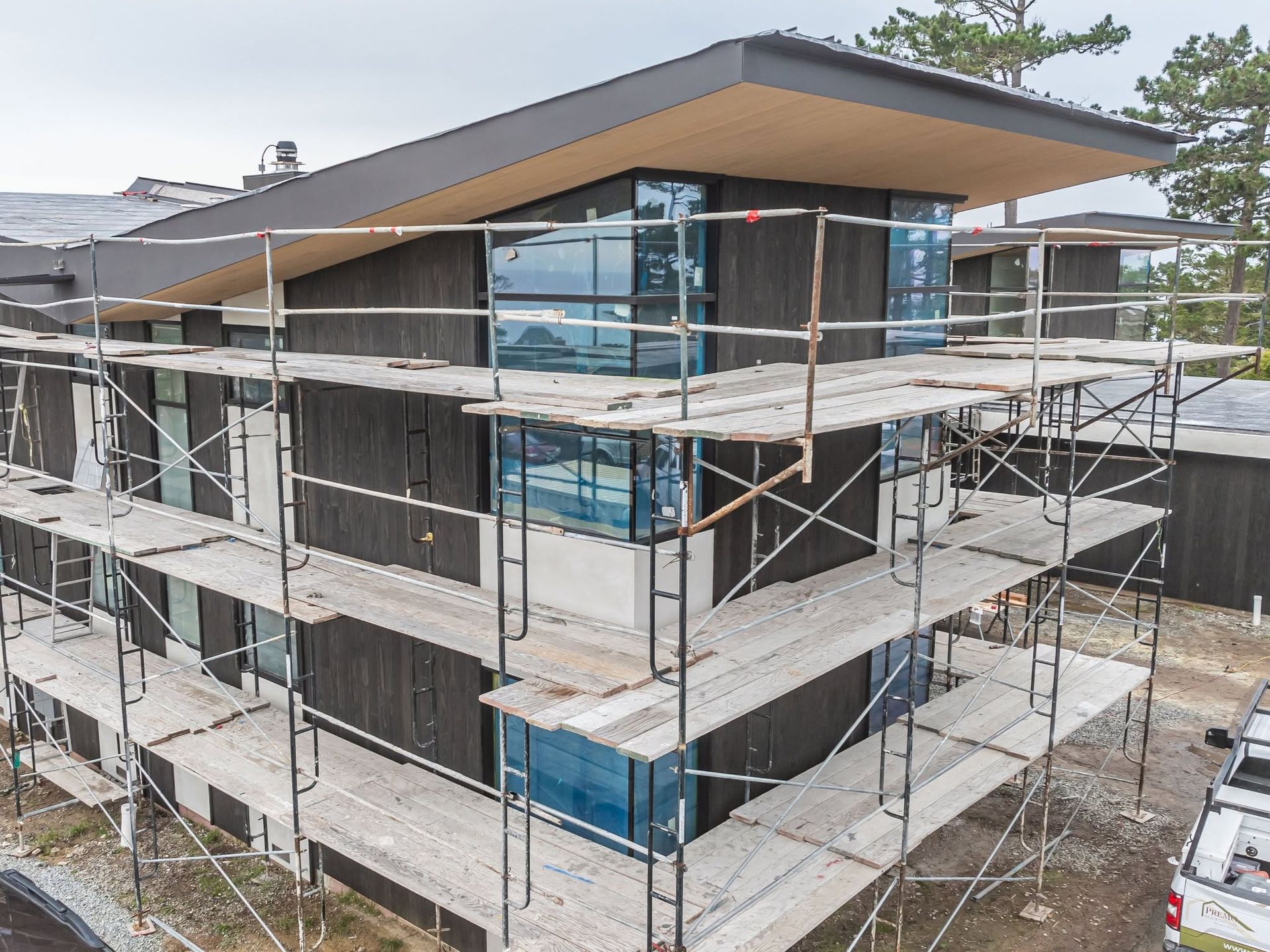 Modern house under construction with scaffolding and blue window coverings