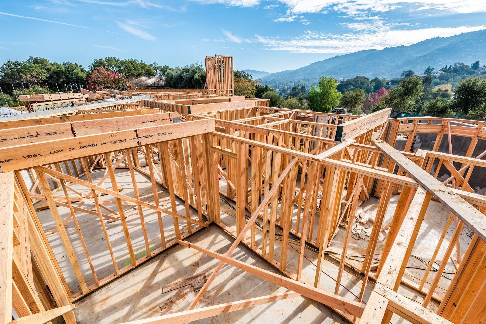Wooden house framing under construction with roof trusses and mountain views in the background