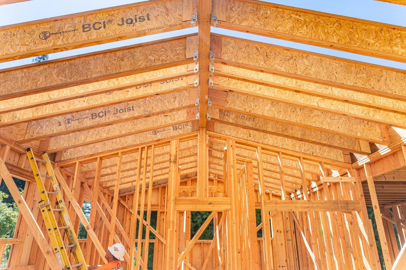 Framed wooden house interior with exposed roof trusses and wall studs under construction