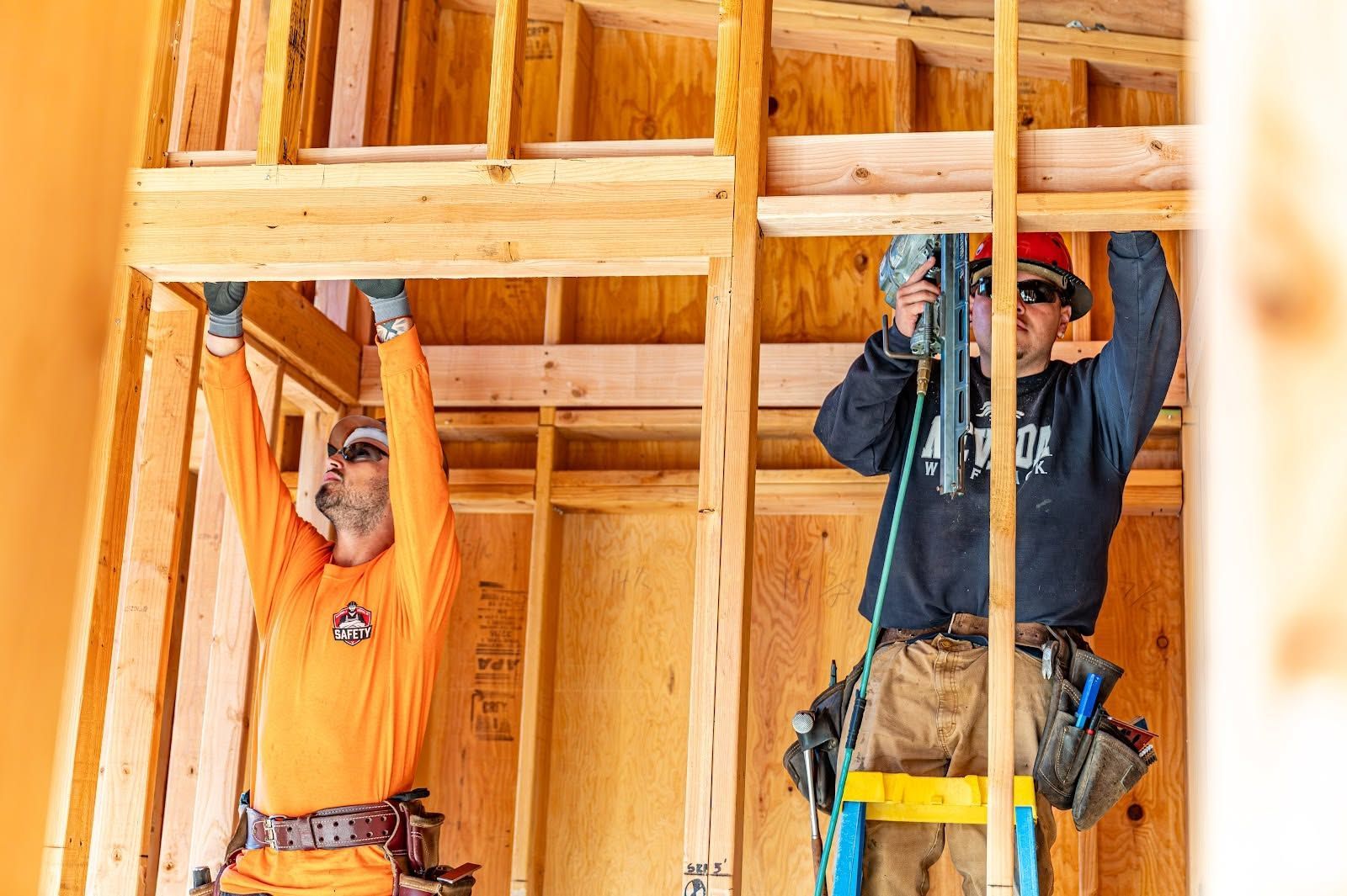 Two construction workers installing wooden framing inside a house under construction