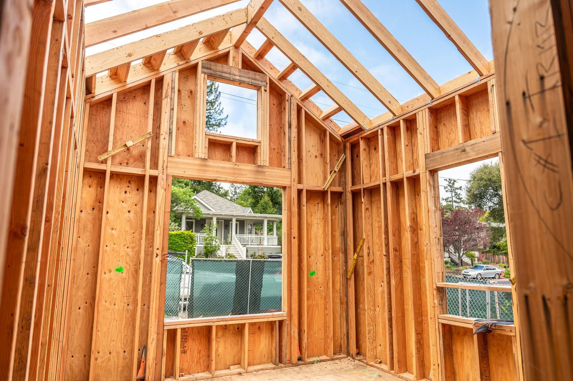 Interior of a wood-framed house under construction with exposed rafters and window openings