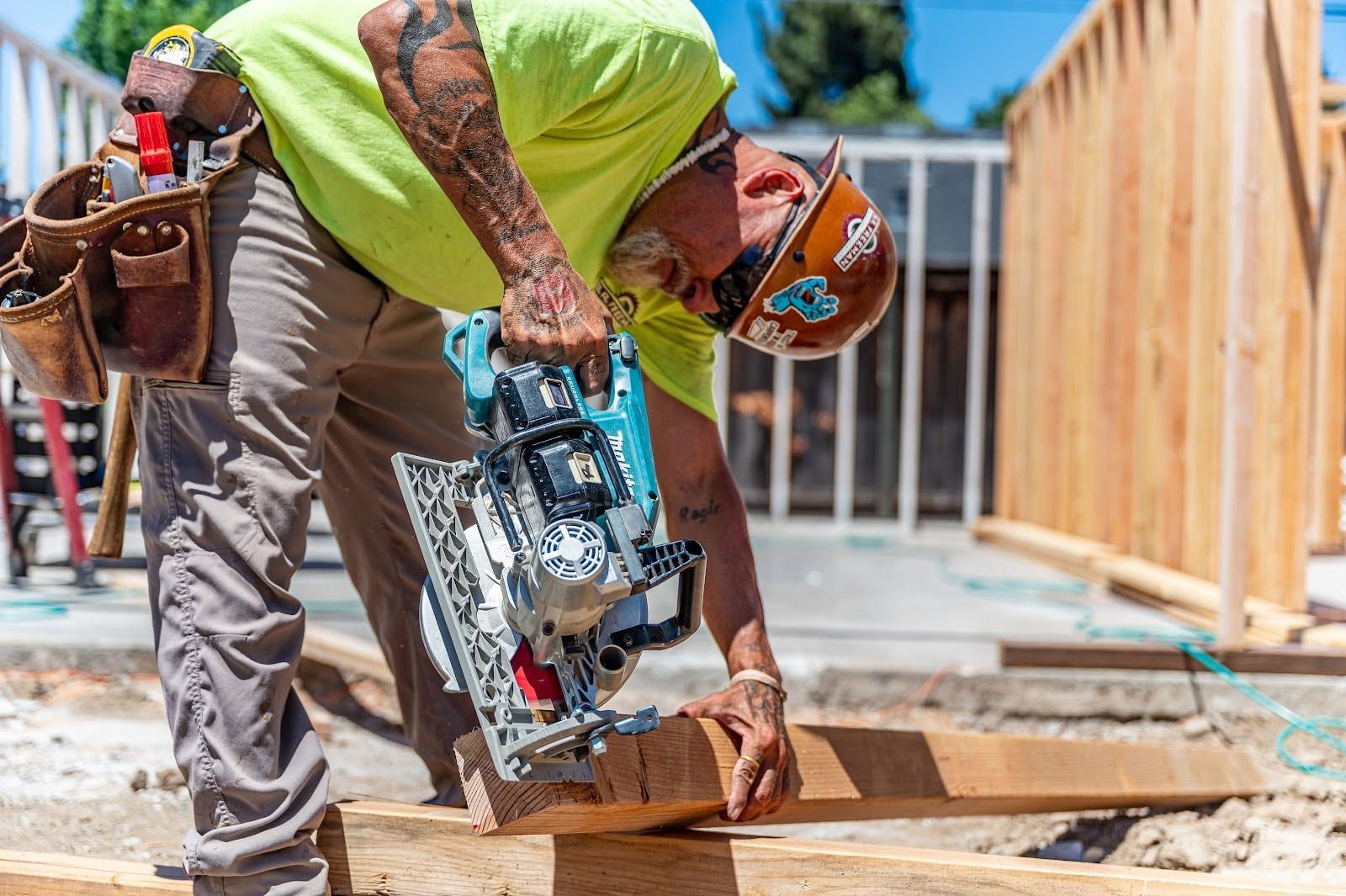 Construction worker measuring and cutting wood on a framed deck with a circular saw